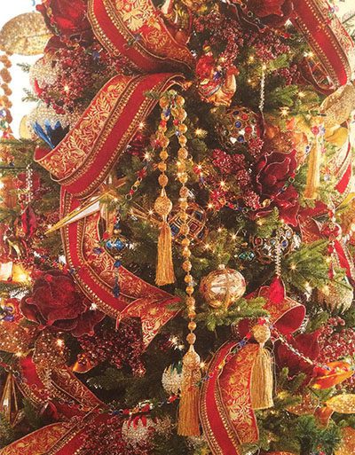 close up of red and gold ribbon woven through a christmas tree with beaded garlands and exquisite glass ornaments