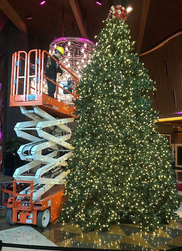 20ft Christmas Tree being assembled in a hotel lobby with a scissor lift