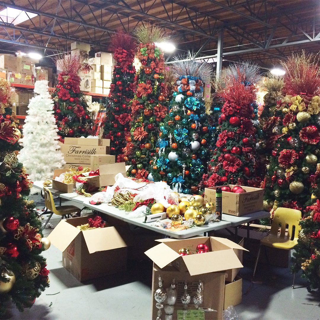 Desk covered in Christmas decor items and surrounded by giant Christmas trees